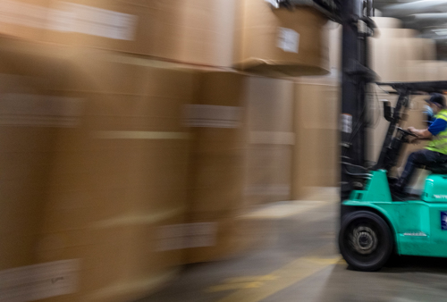 Inside a paper store, we see stacked reels of paper stock and a fork lift.